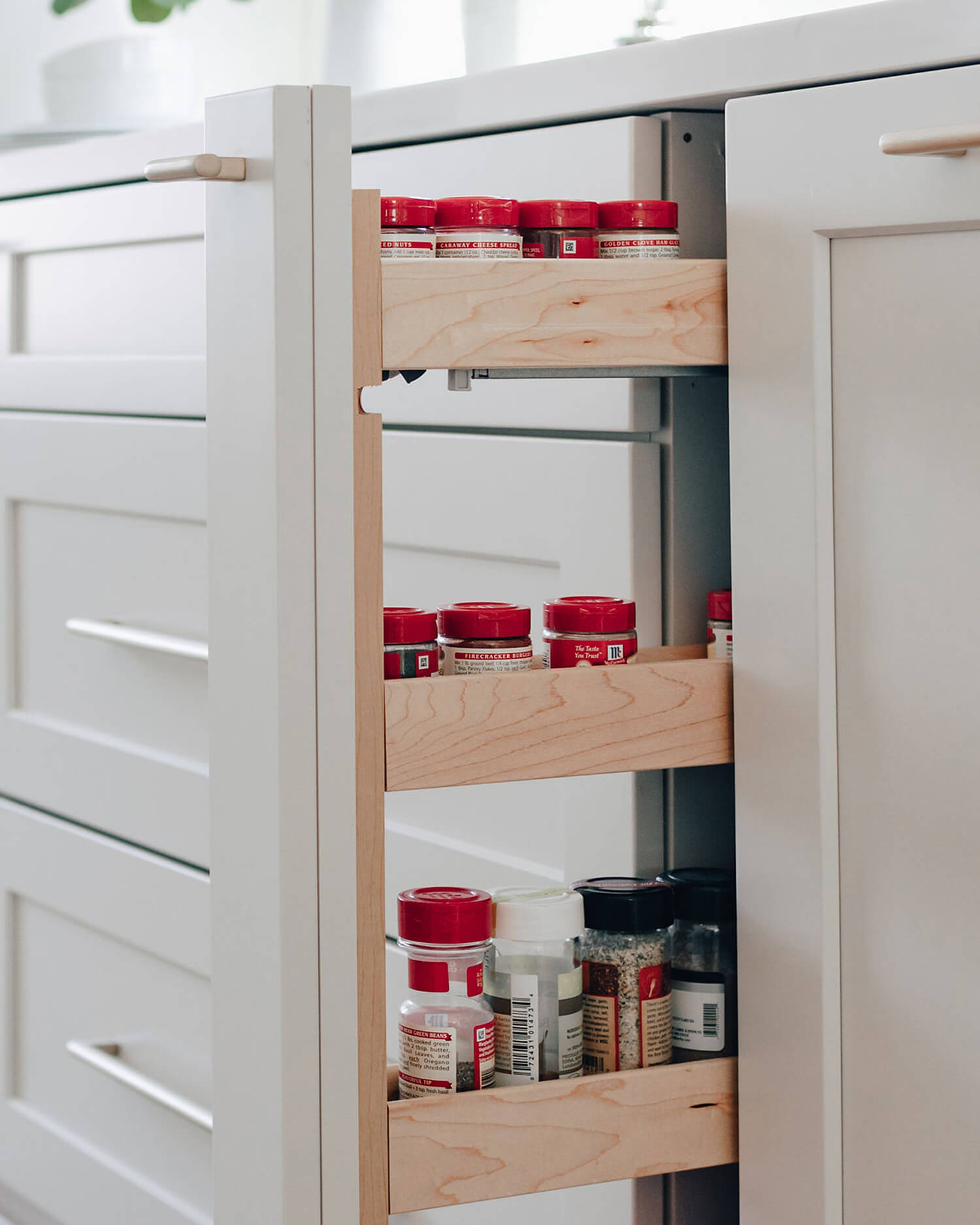 Cabinet storage accessories like a thin pull-out spice rack keep seasonings organized and within easy reach of the kitchen prep zone. Integrated into custom kitchen cabinets, this smart storage solution maximizes space while supporting an efficient cooking workflow.
