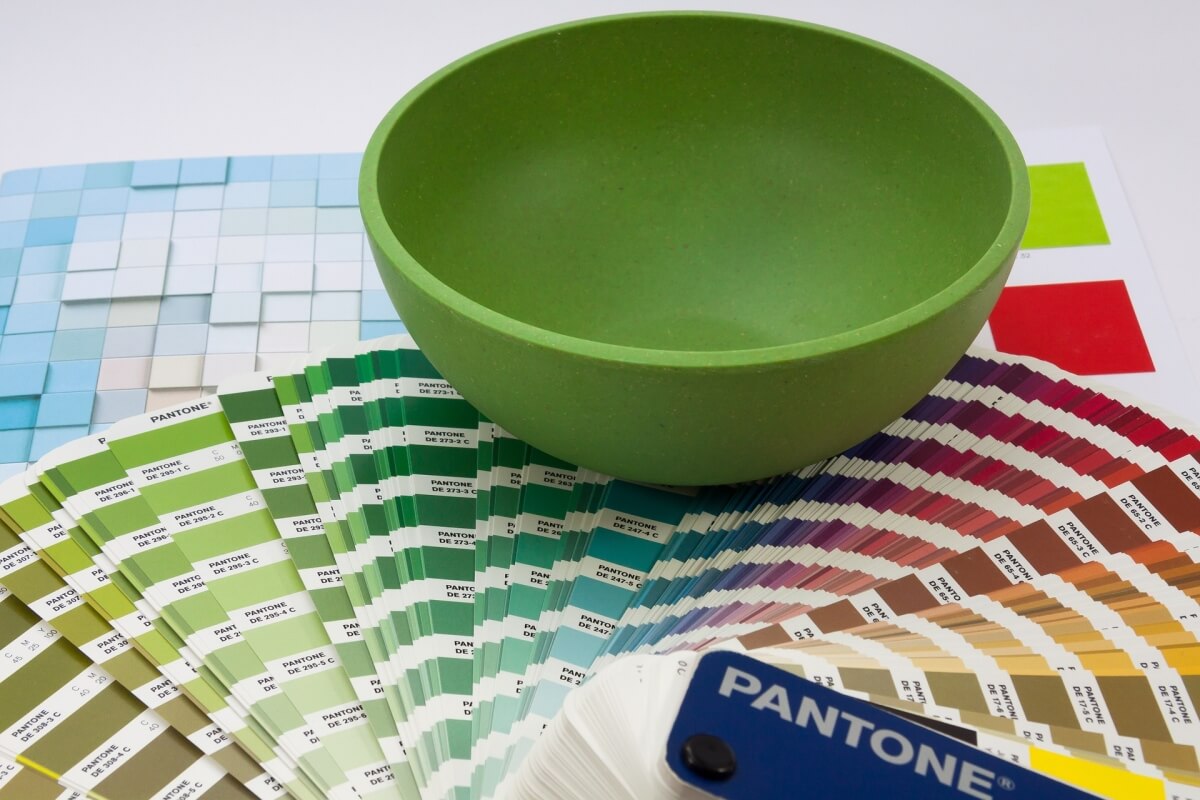 A kitchen designers desk with interior design tools including a pantone color book with paint color samples and ideas.