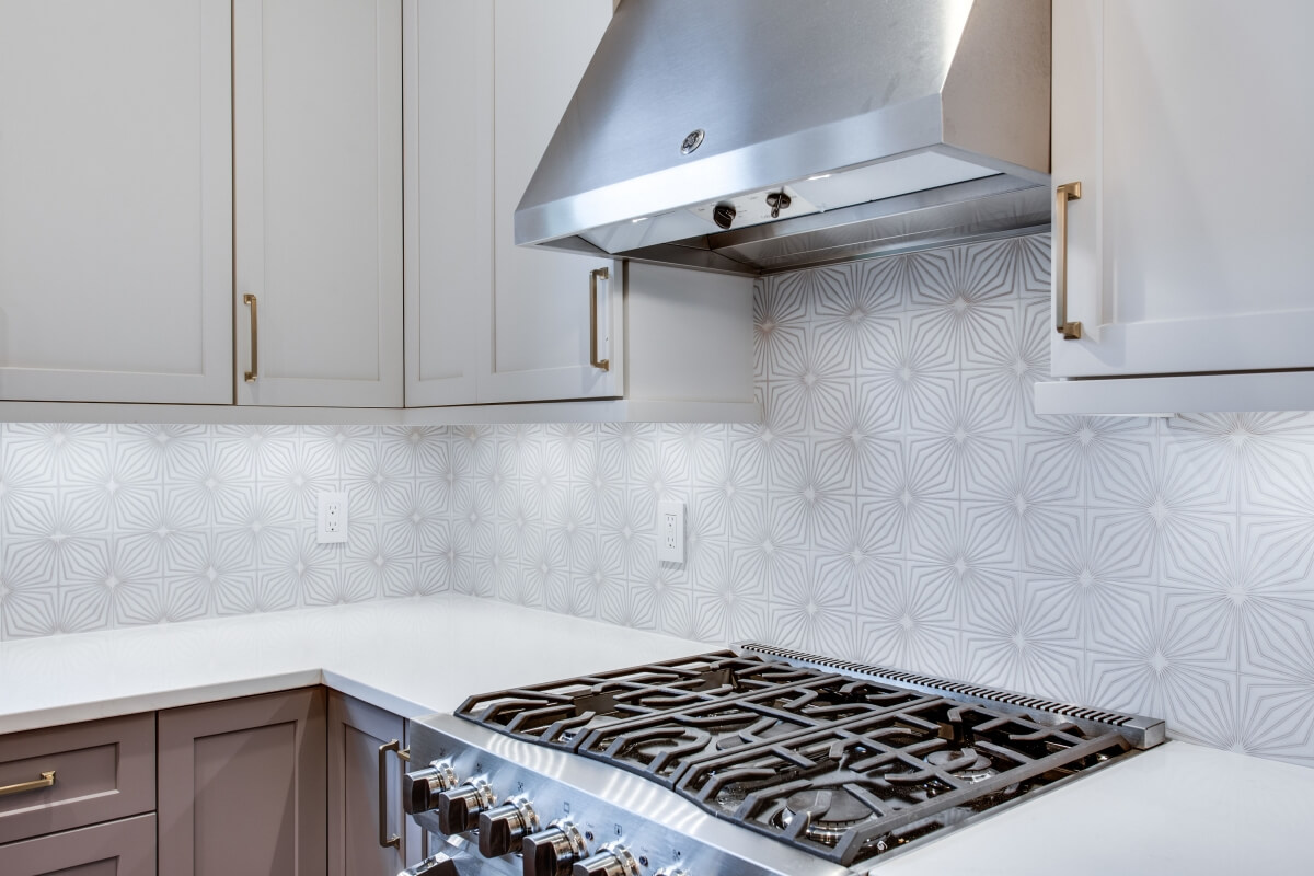 The purple-gray lines in the starfish pattered Fireclay Tile ties the two-toned cabinetry together beautifully.