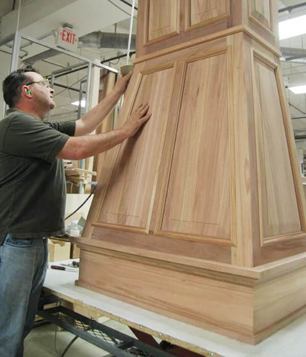 One of our Master Builders doing a final sanding on this custom-designed wood hood prior to finishing.