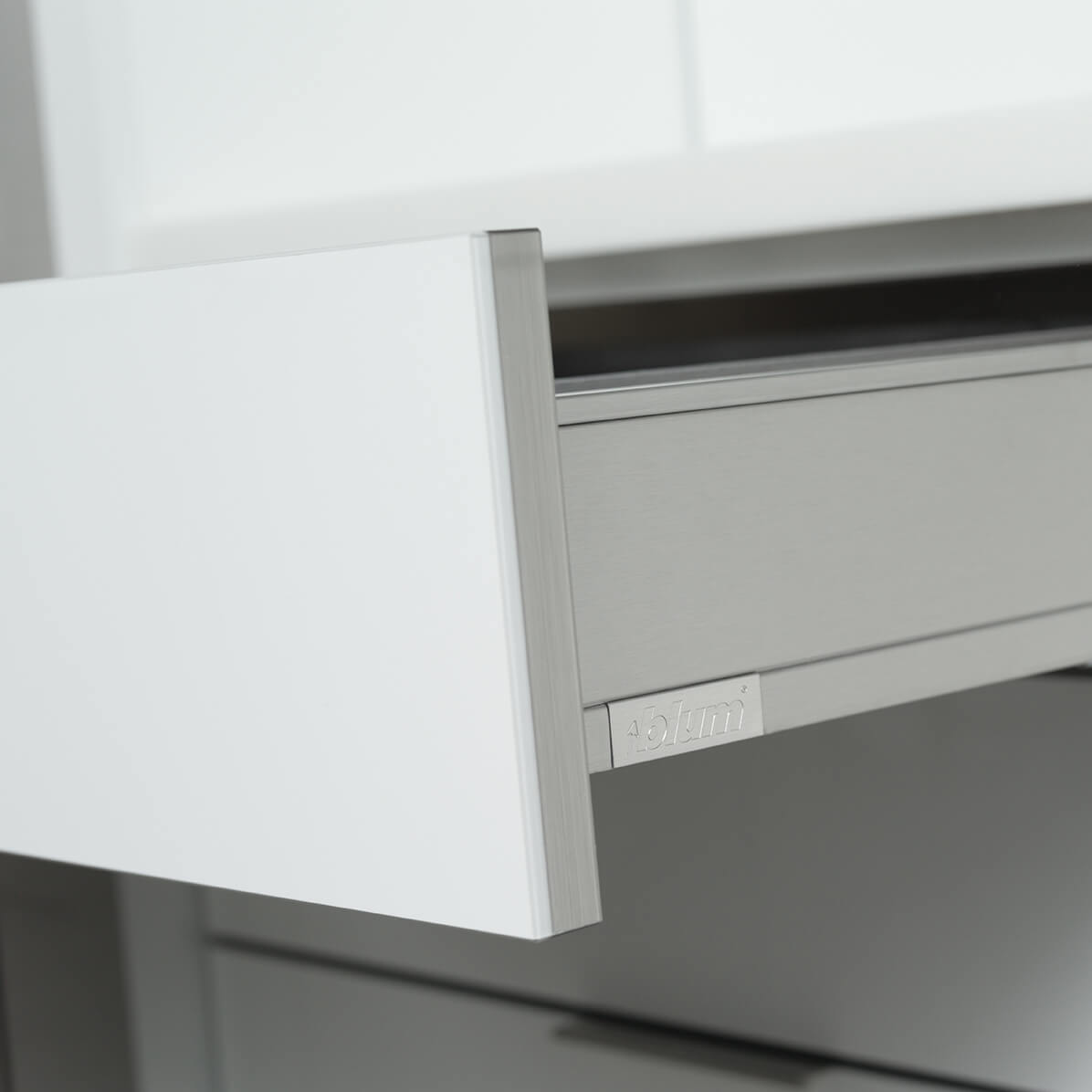 A close up of a stainless steel drawer with contemporary kitchen cabinets with an acrylic finish.