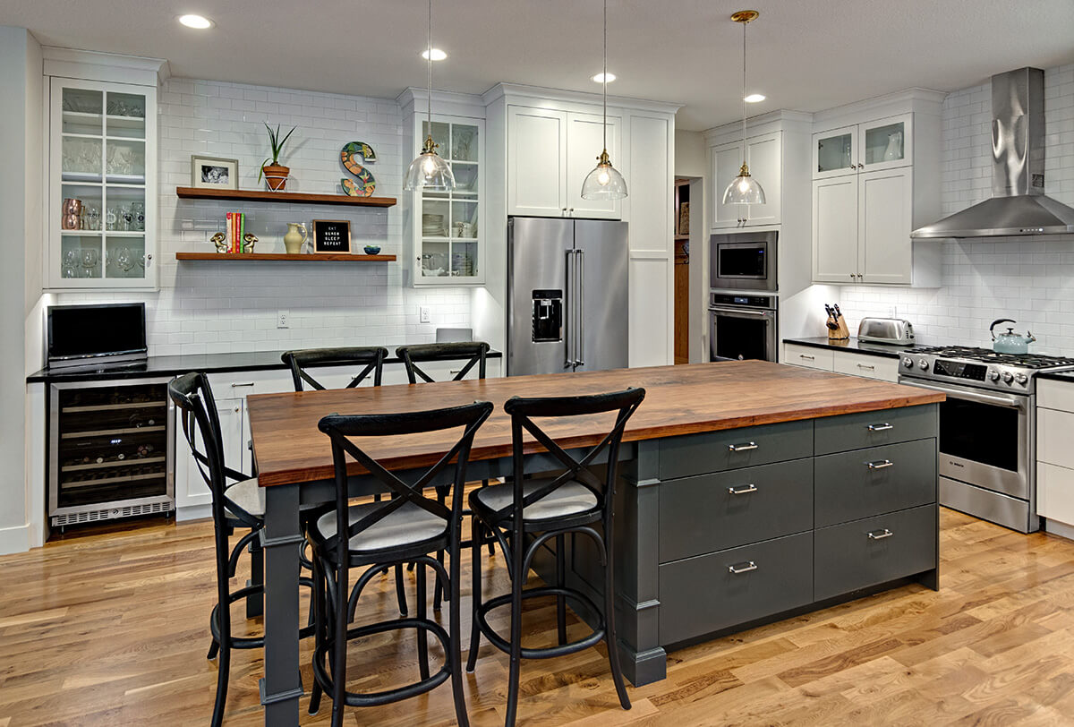A white and gray painted kitchen with dark gray kitchen island and medium wood foors.