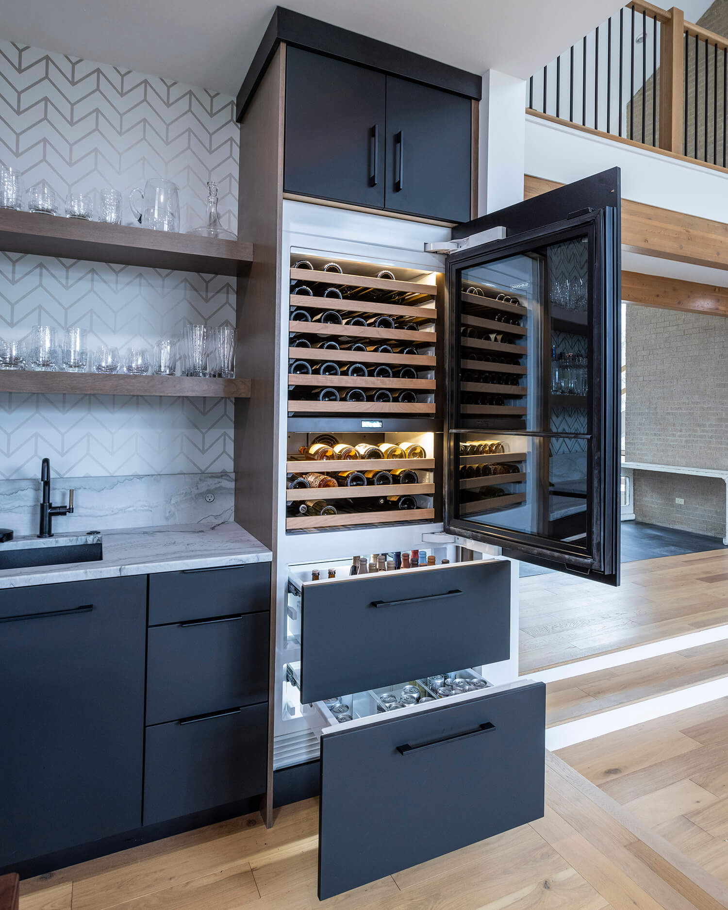 A multi-layer beverage fridge and icemaker drawer with custom appliance panels.