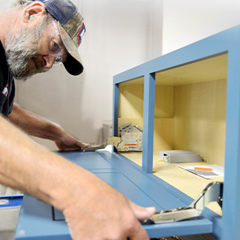 A cabinet maker hard at work crafting premium semi-custom and custom kitchen and bath cabinets. Made in America.