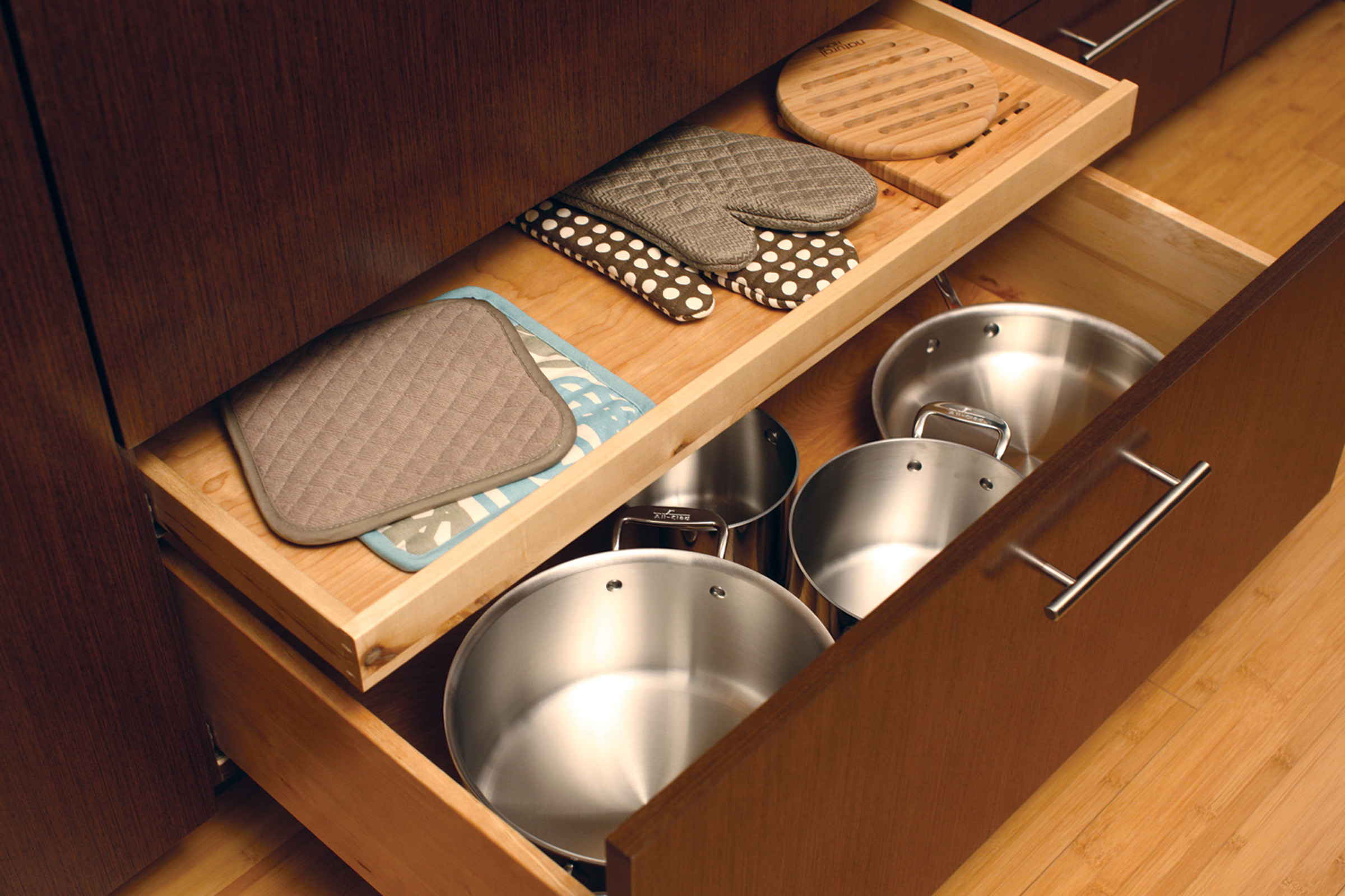 Conveniently store oven mitts and potholders in a Dura Supreme shallow roll-out above a pot and pant drawer (ROSAD).