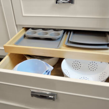 Shallow Roll-Out Above Drawer used for Pan Storage. Kitchen cabinets and storage by Dura Supreme Cabinetry.