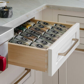 A neatly organized spice rack cabinet drawer in a cottage style kitchen makes the labels easy to read.