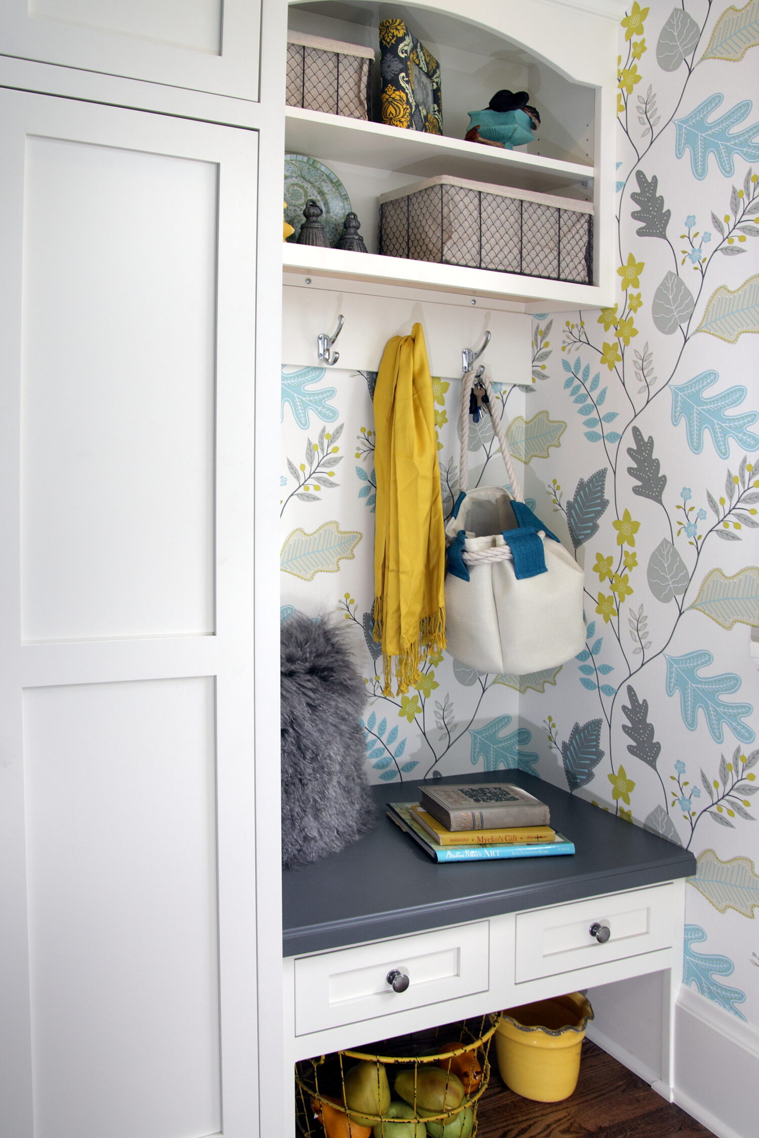 A fun an colorful small entryway cabinet with drawers and a bench next to a tall entry way cabinet for coat storage.