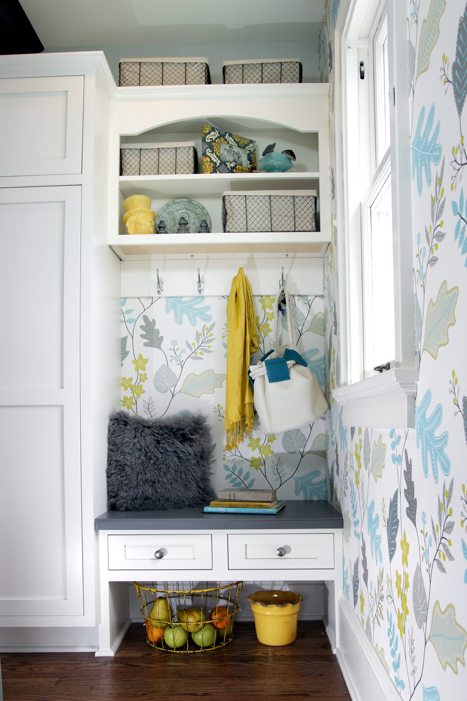 A small entryway storage cabinet with a boot bench with two small drawers and a tall cabinet for hanging coat storage.