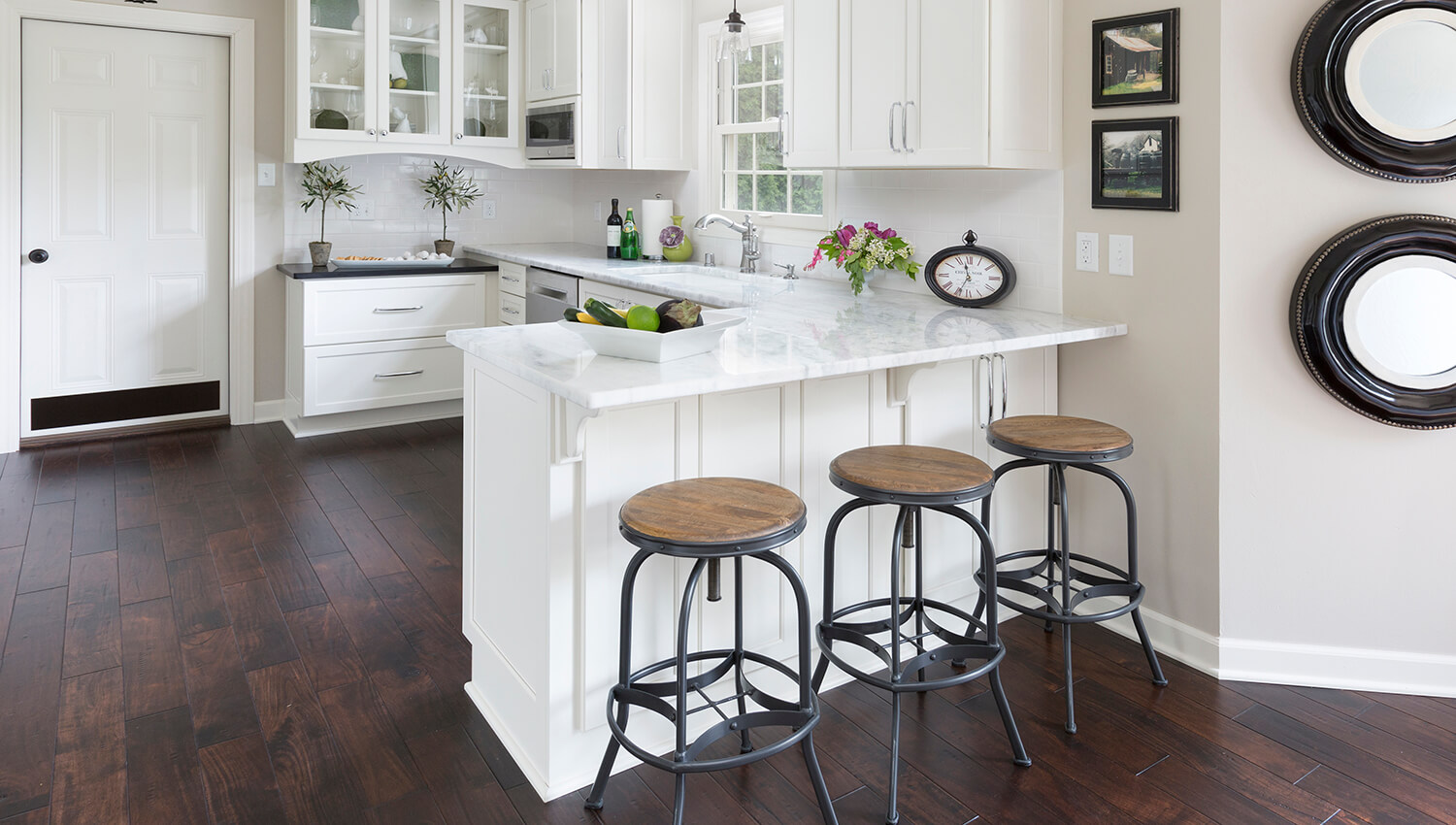 A bright white kitchen with a peninsula that has seating for 3 bar stools and lots of storage.