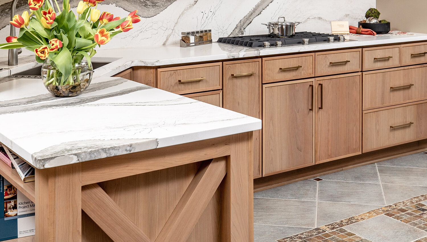 A peninsula kitchen featuring light stained wood cabinets with a skinny shaker door style and an X patterned end cap at the end of the peninsula cabinet.