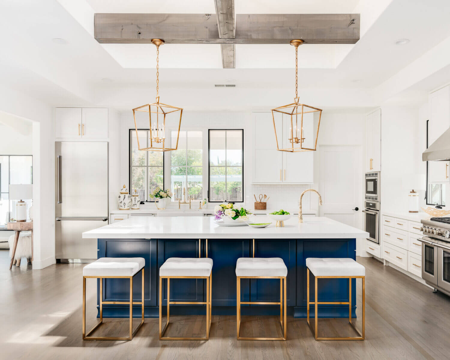 A bright white and navy blue trendy kitchen design with gold and bass hardware & light fixtures.