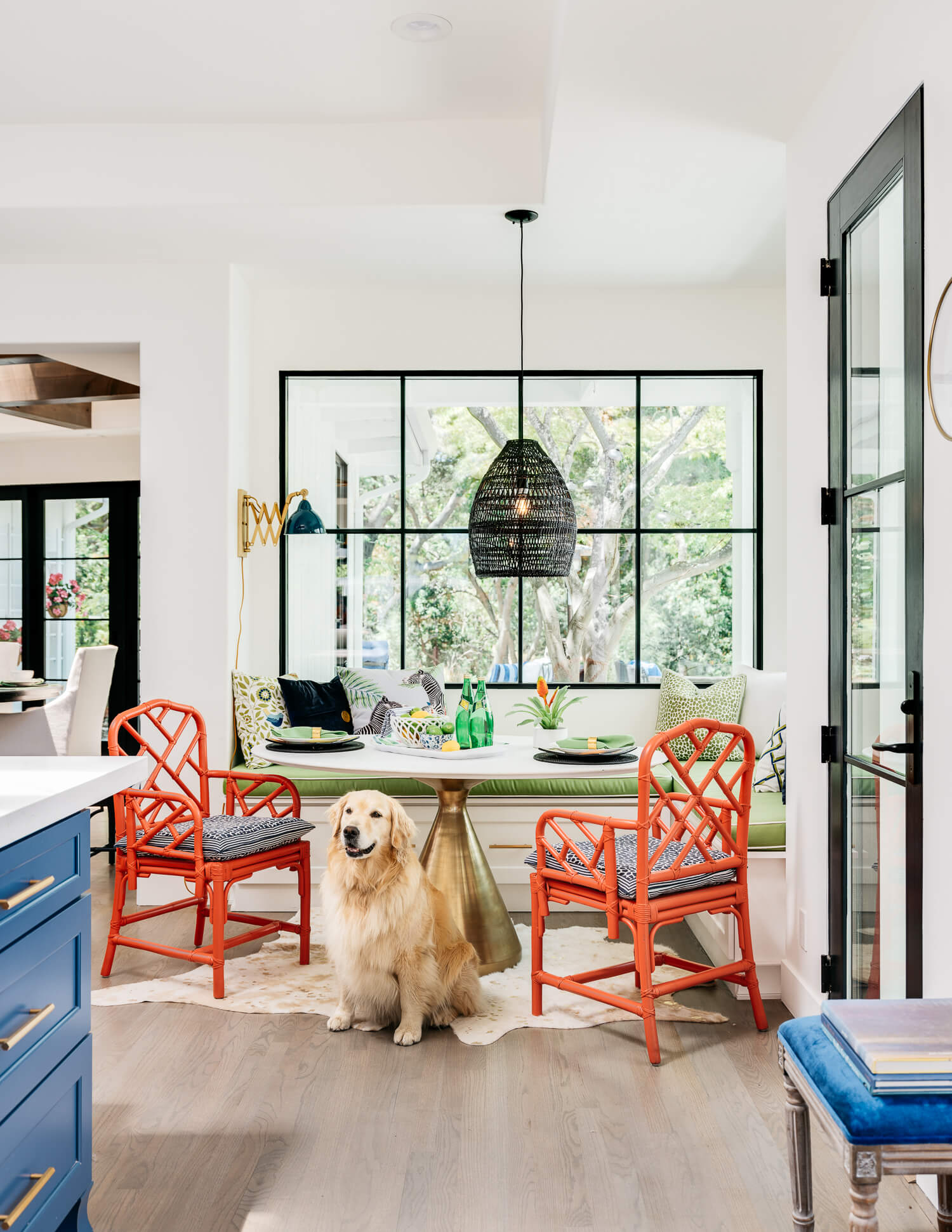 A happy dog in a beautiful kitchen remodel standing by the breakfast nook seating area with a built-in banquette table just off the kitchen and near the blue-painted kitchen island.