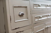 A close up of the distressed cabinets on a kitchen island with the Marley-Inset door style in a Heritage Paint “K” finish on Knotty Alder.