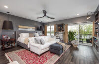 A gray master bedroom with a dark stained wood floor.