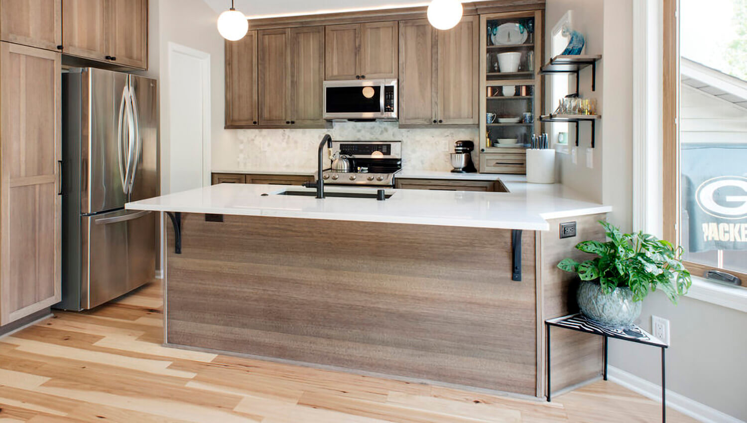 This remodel project features an angled kitchen island that bumps out around a window and gray stained hickory cabinets from Dura Supreme. 