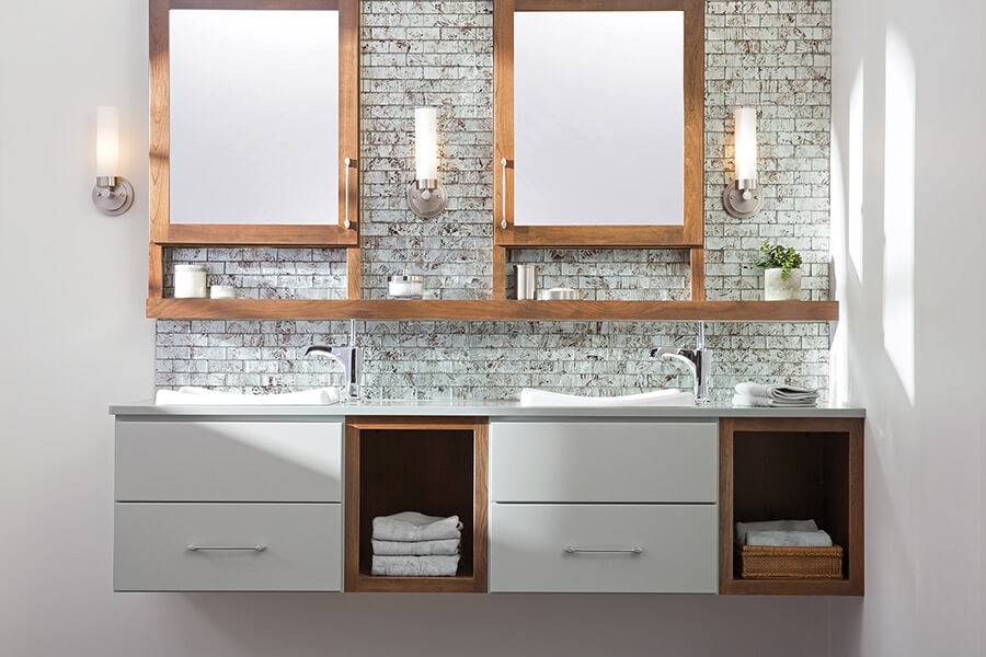 A two-toned floating vanity with light gray paint and warm stained wood with open storage and a floating shelf connecting to the dual medicine cabinets with a modern design.