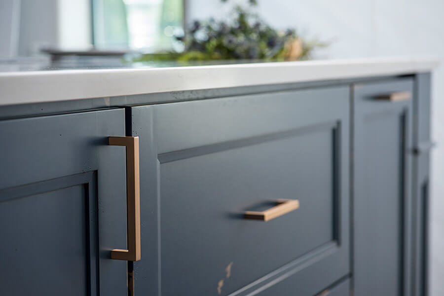 A kitchen island with a distressed painted finish in a trendy navy blue color. Shaker cabinet doors have a delicate detailed profile. This kitchen design features a custom Heritage Paint finish by Dura Supreme Cabinetry.