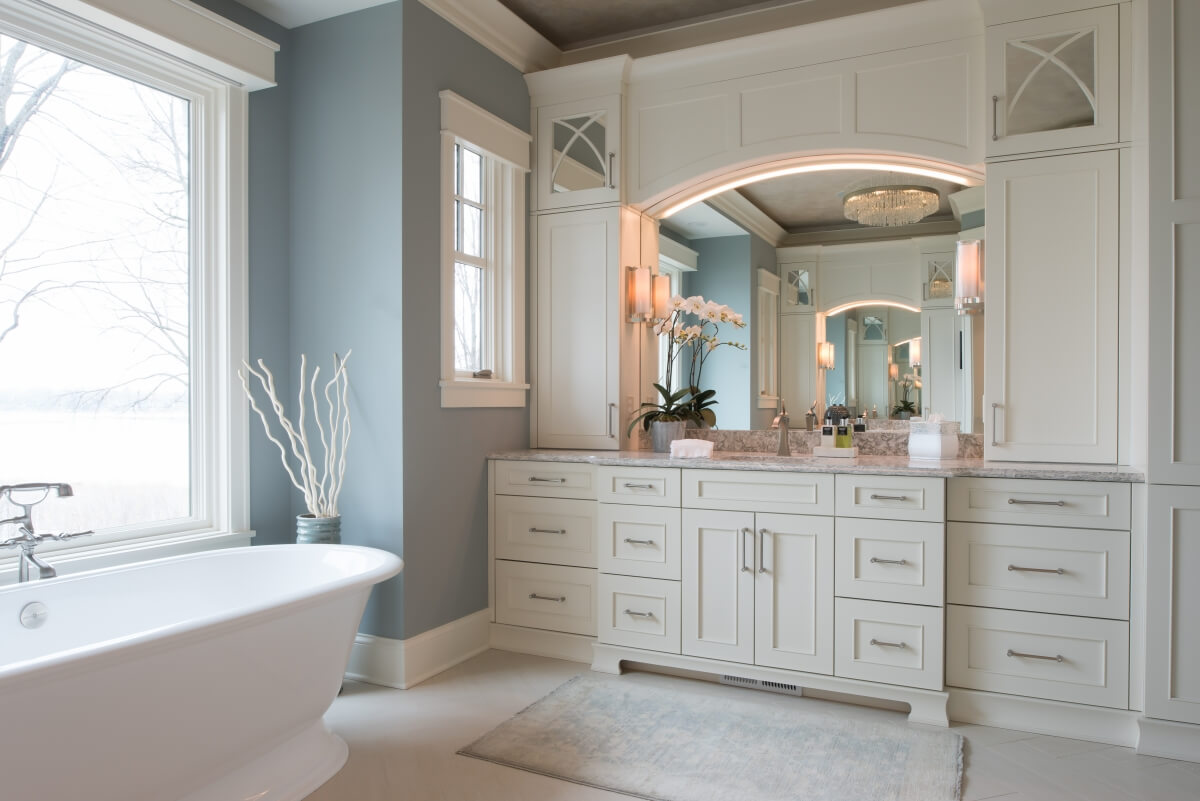 The upper cabinets use mirror to create the look of a glass accent door without the hassel of having to keep what's behind the cabinet neat and tidy. Dura Supreme master bathroom design by Michels Homes, Minnesota. Photography by Landmark Photography.