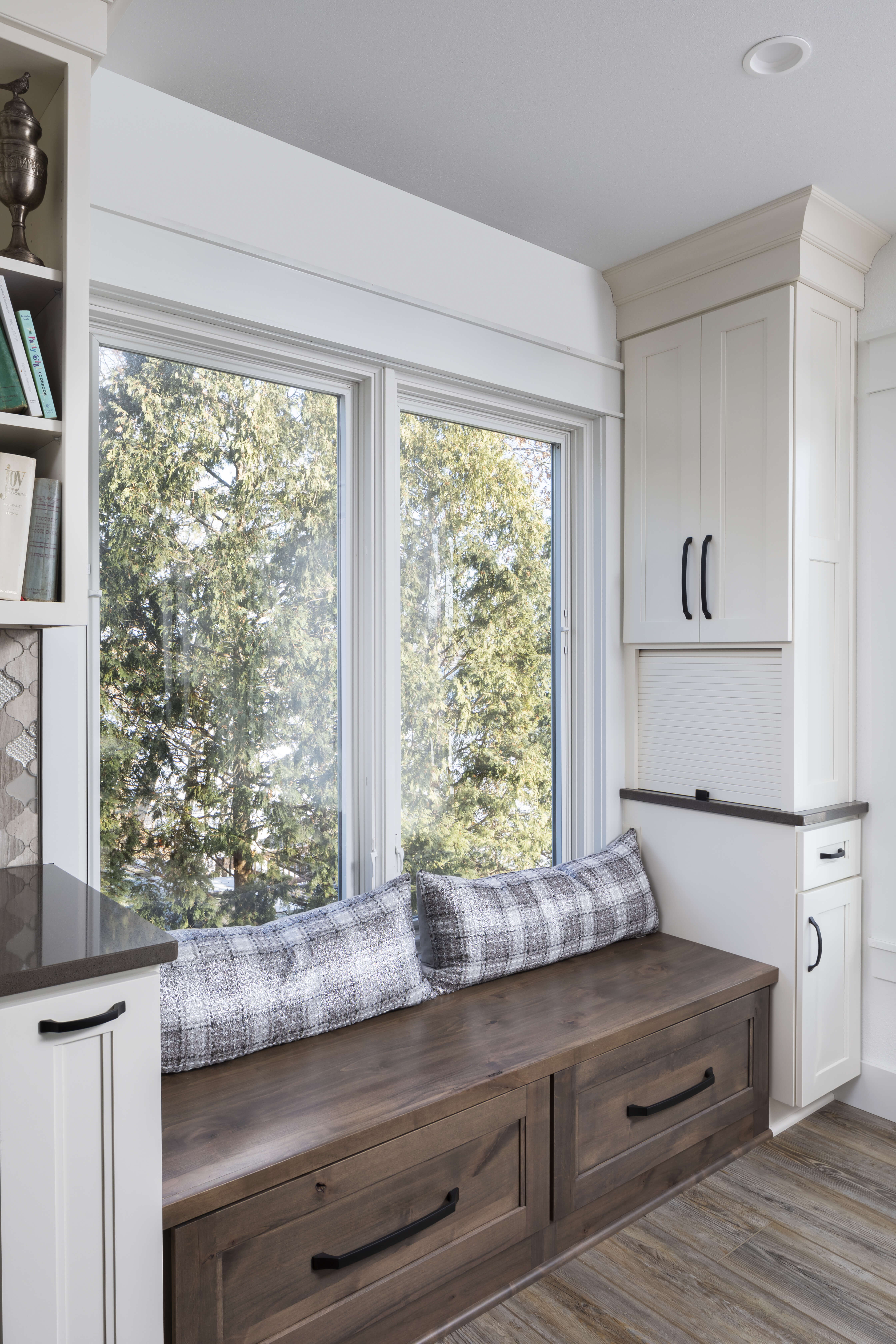 A boot bench under a window with towers of storage to house a mini home office and office supplies.