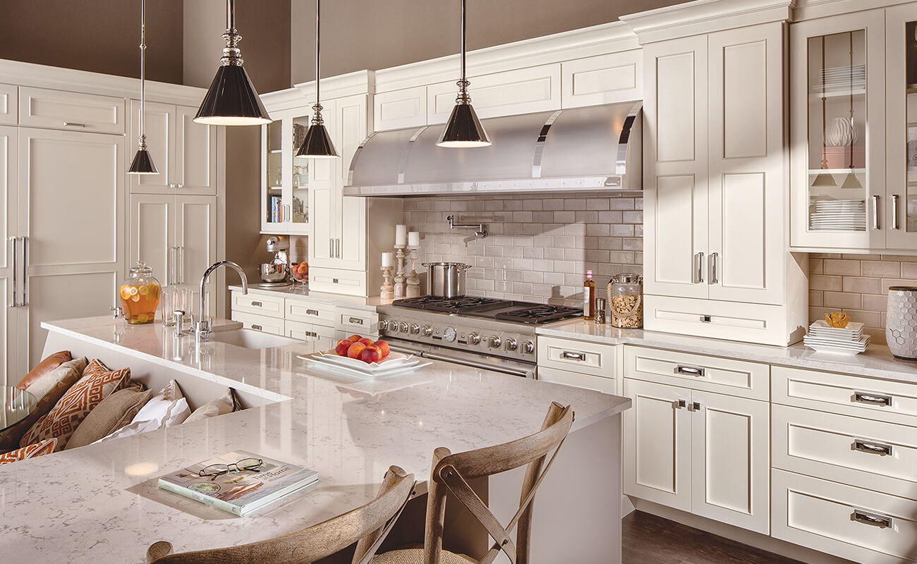 This kitchen design has a transitional style featuring framed cabinet construction method with white painted semi-custom and custom kitchen cabinets from Dura Supreme Cabinetry.