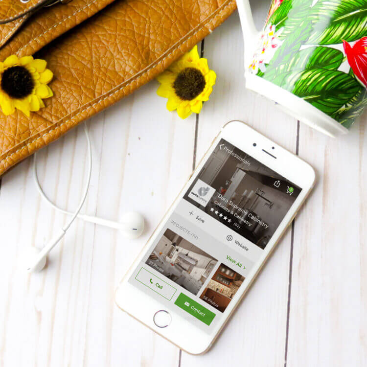 A cell phone on a desk with the mobile app Houzz showing Dura Supreme's Houzz profile.