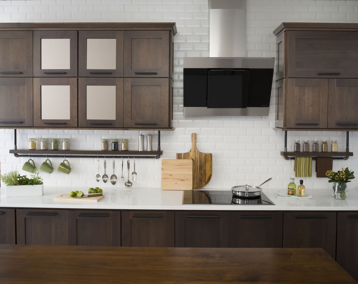 A modern industrial styled kitchen design with pipe floating shelves for spices, dark stained cabinets, and decorative bronze mirror cabinet doors.