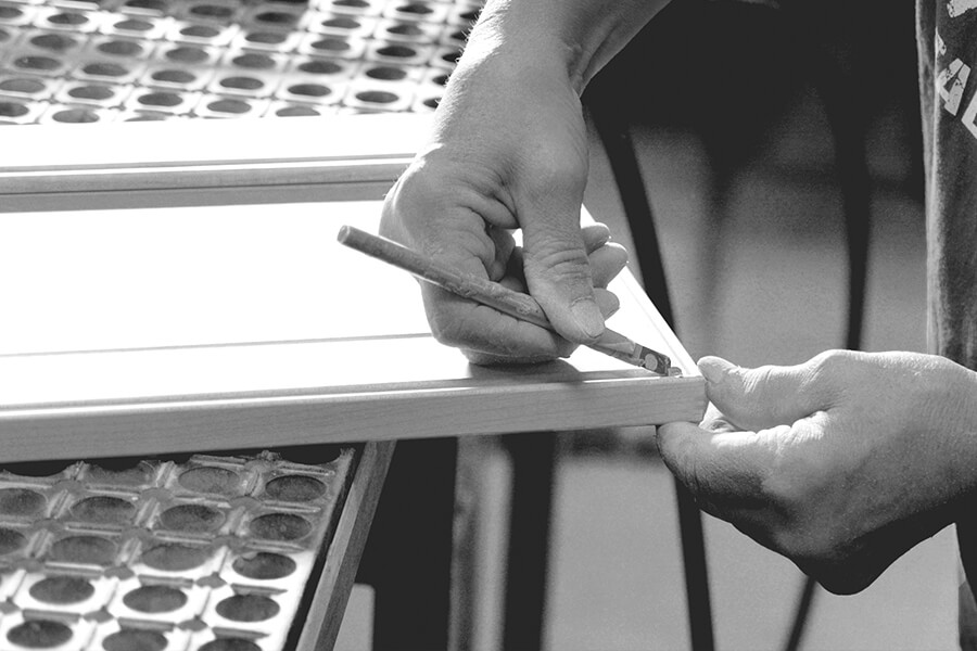 A cabinet maker hand-detailing the corners of a cabinet door within the Dura Supreme factory located in Minnesota, USA. We are proud to craft American made semi-custom and custom kitchen cabinets.