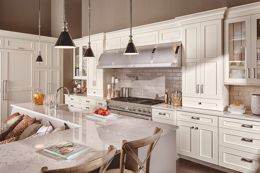 A delightful all white kitchen with white painted cabinets and white quartz wountertops featuring Crestwood Framed Cabinetry by Dura Supreme. Dura Supreme’s Crestwood cabinetry offers a traditional American-style construction with an aesthetic that finds itself at home in any setting. Full-Overlay, Standard Overlay and Inset doors complement a vast array of finish and design possibilities.