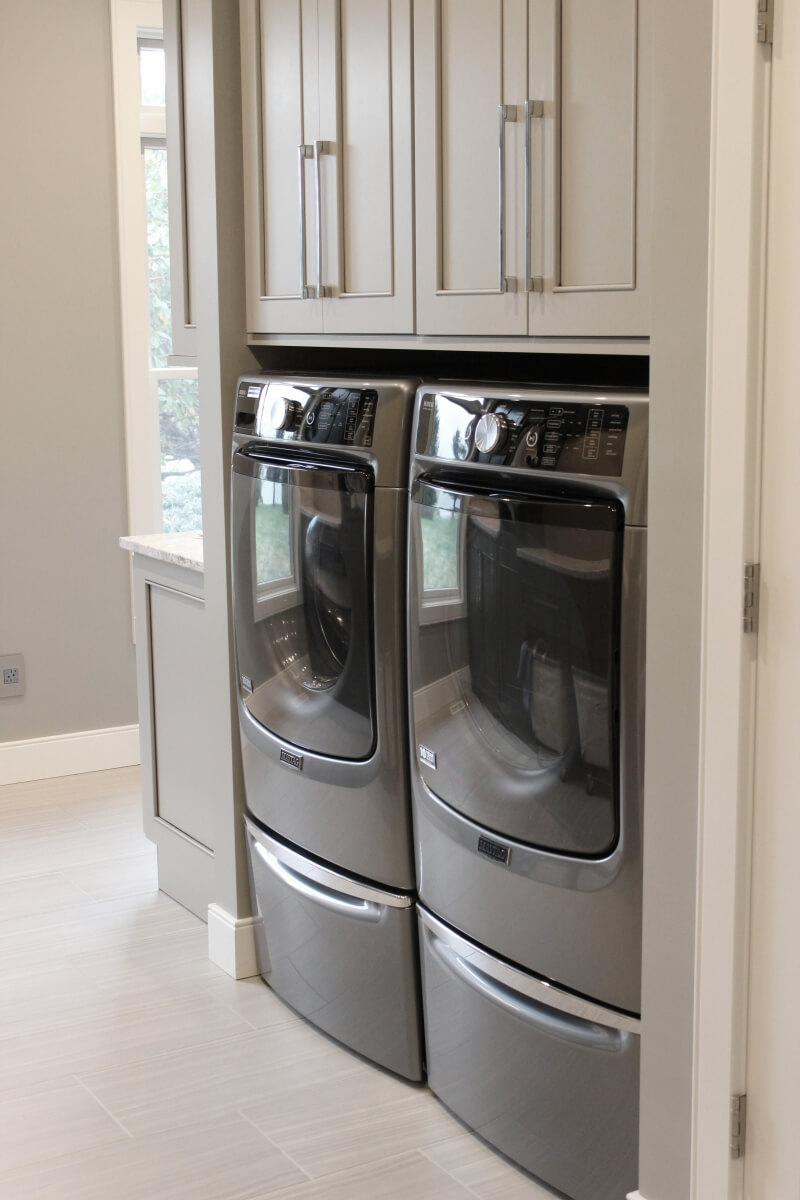 A warm gray painted laundry room with gray painted cabinets.