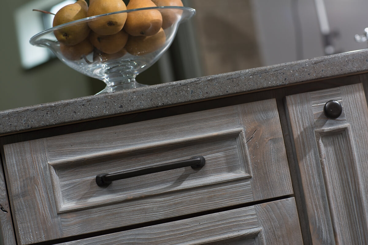 A close up of driftwood inspired weathered wood cabinets from Dura Supreme Cabinetry with a light gray stain.