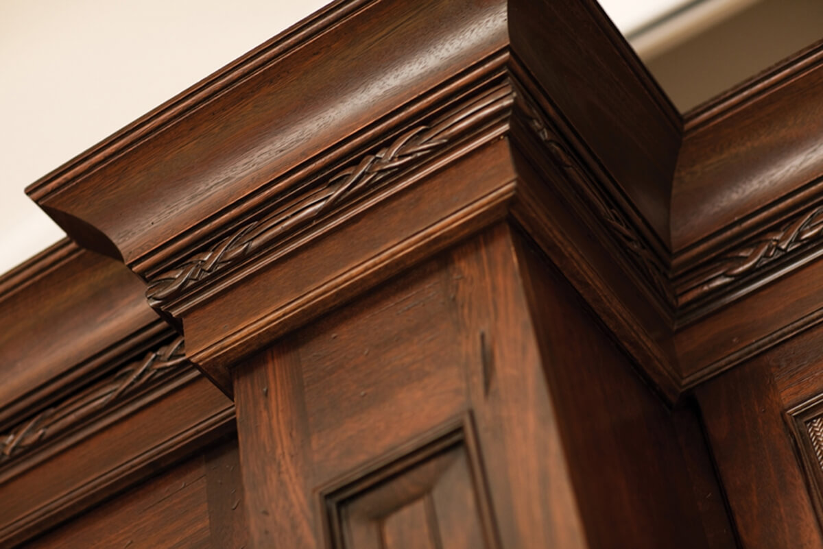 Close up of the top molding on tropical styled kitchen cabinets. An intricate carved molding accents the molding stack.