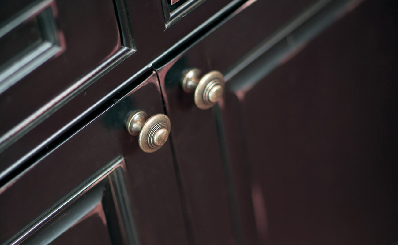 A custom artisan cabinet finish with distressed black painted finish with a rub thru affect on the corners and details.