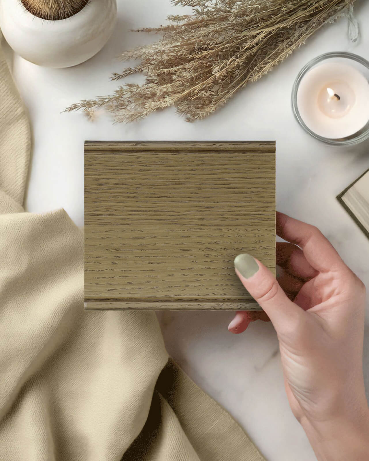 This sample of Desert Sand stain on Quarter-Sawn White Oak held in a woman's hand highlights the natural beauty of horizontal grain slab door cabinetry. Subtle taupe undertones, distinctive wood character, and continuous grain movement make this finish a timeless choice for modern custom cabinets.