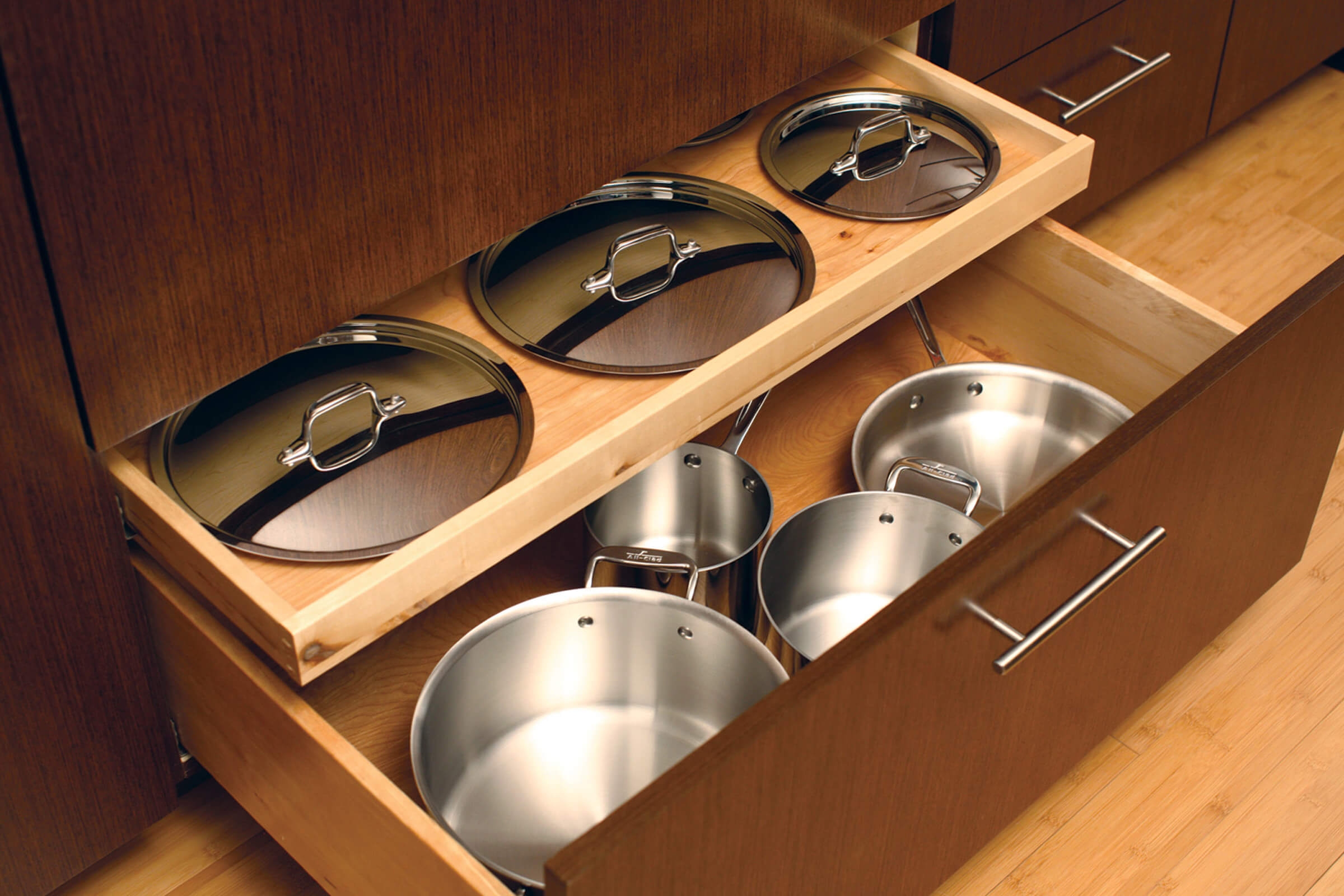 A Shallow Roll-Out Above Drawer neatly stores the lids for the pots and pans that are stored in the deep drawer below.