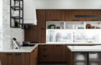 A modern loft that was remodeled with frameless cabinets from Dura Supreme with walnut veneer, a white modern hood and black metal shelves.