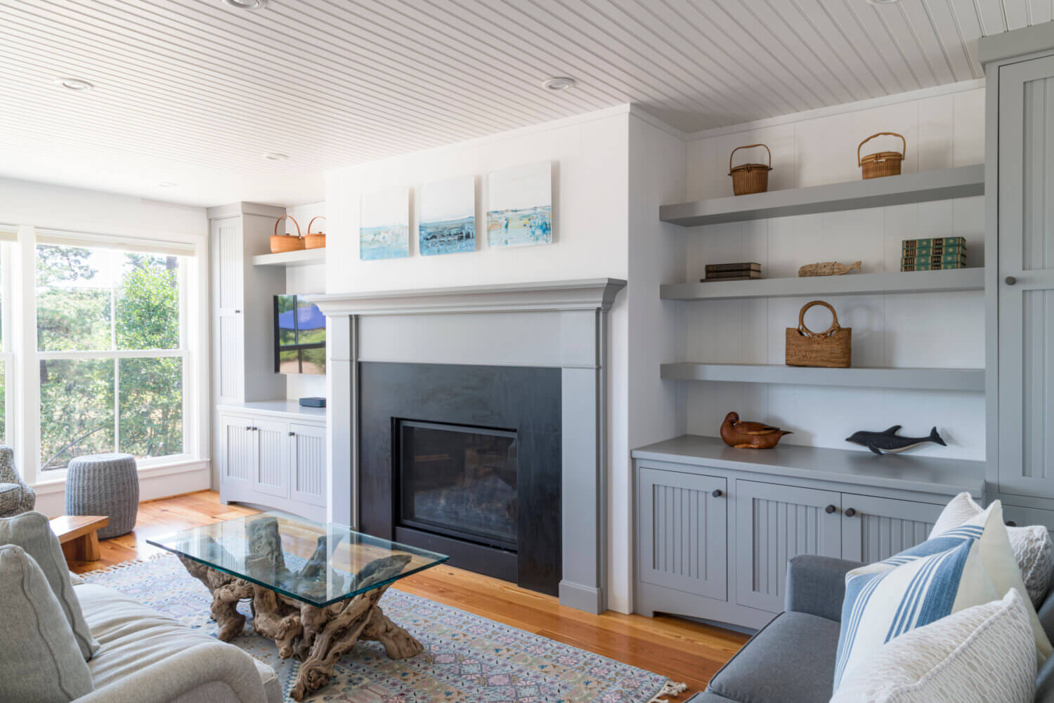 A living room with a full wall of gray built-in bookcase cabinets centered around matching gray fireplace mantel custom crafted by Dura Supreme.