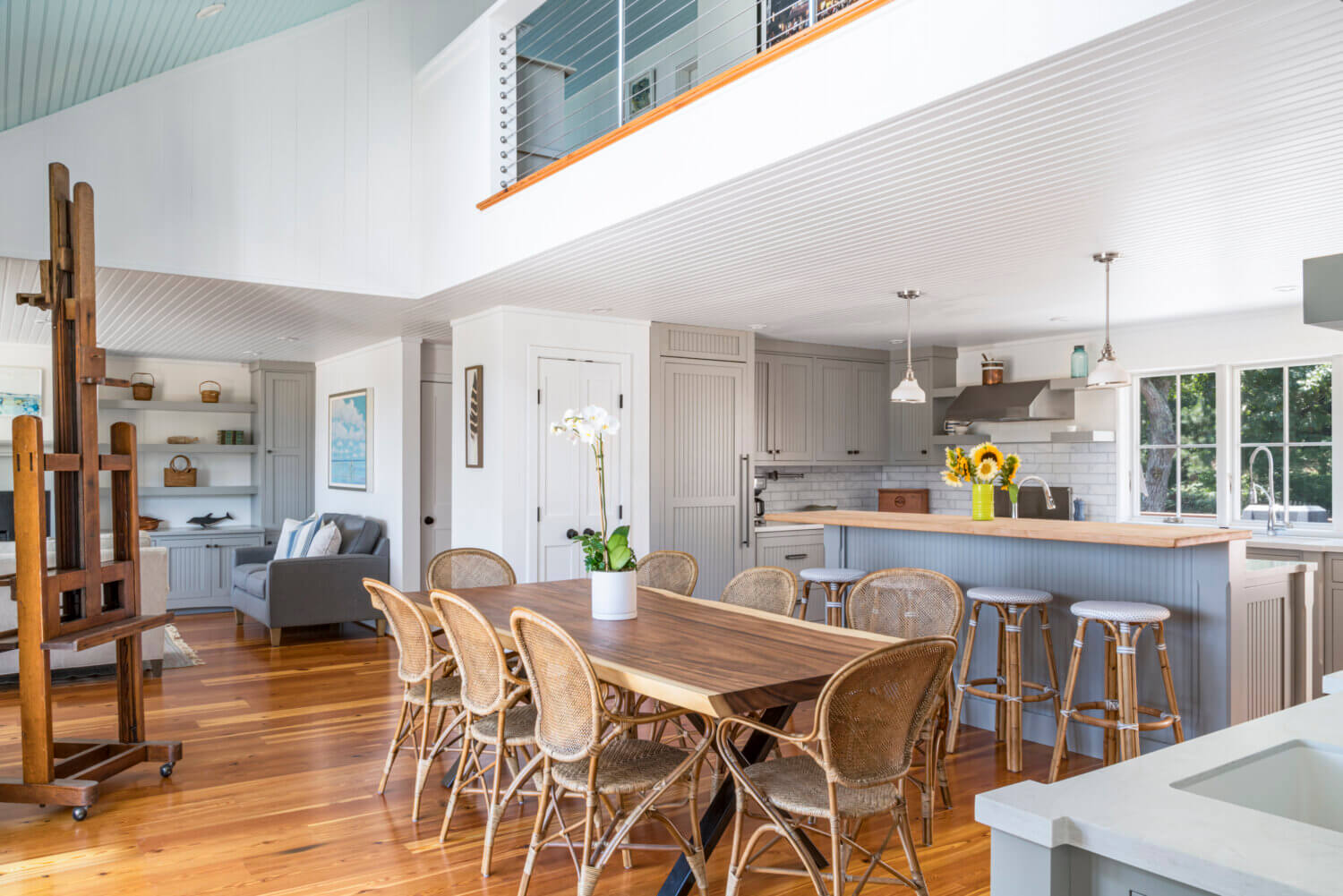 A beach home with an open loft above the remodeled kitchen with gray inset cabinets with beaded panel doors.