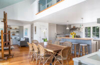 A beach home with an open loft above the remodeled kitchen with gray inset cabinets with beaded panel doors.