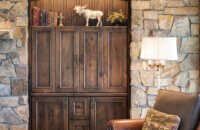 A built-in entertainment center surrounded by a decorative rock wall in a rustic living room design.