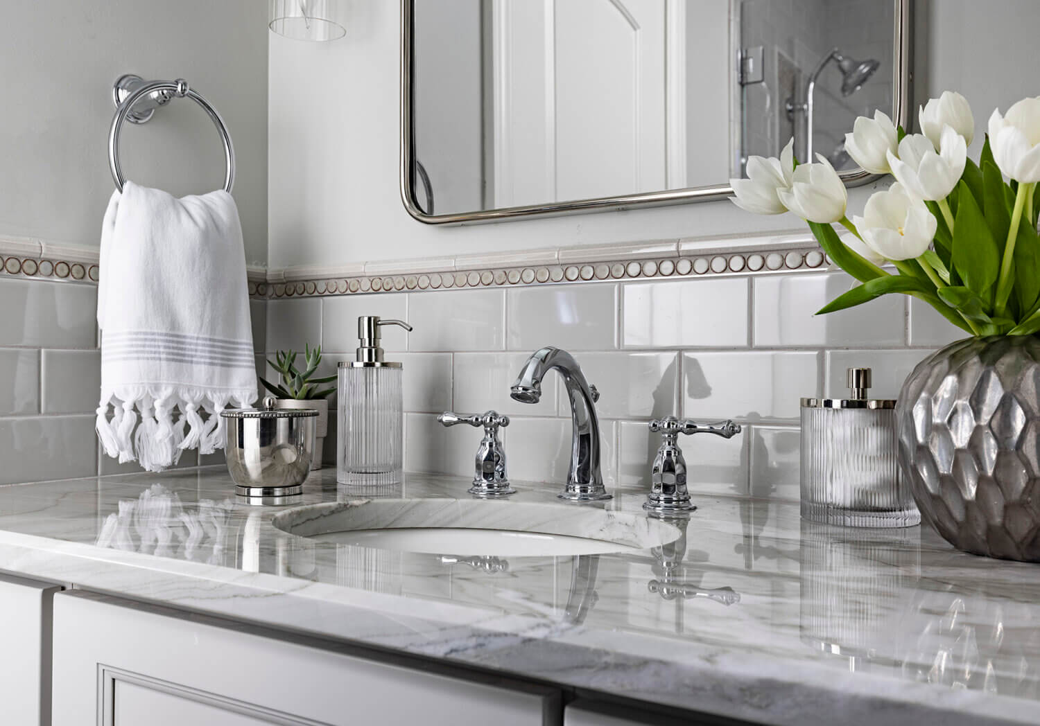 A close up of the sink area of the gray vanity with a light gray countertop and nickel faucet.