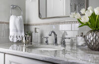 A close up of the sink area of the gray vanity with a light gray countertop and nickel faucet.