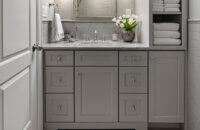 All gray bathroom design with a small gray vanity with a tall and thin tower on thr right side of the sink.