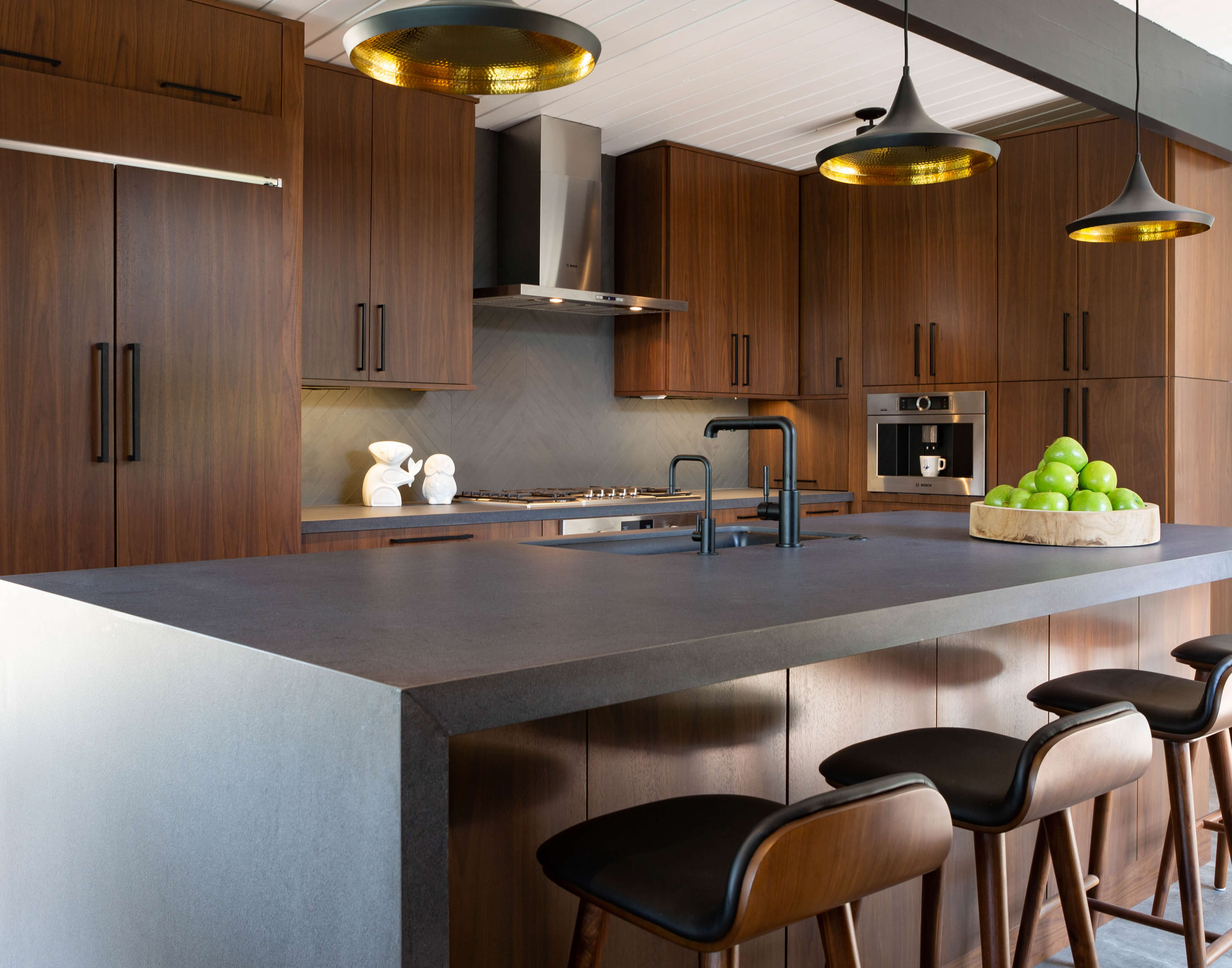 A dark walnut kitchen with a mid-century modern design style and a waterfall kitchen countertop.