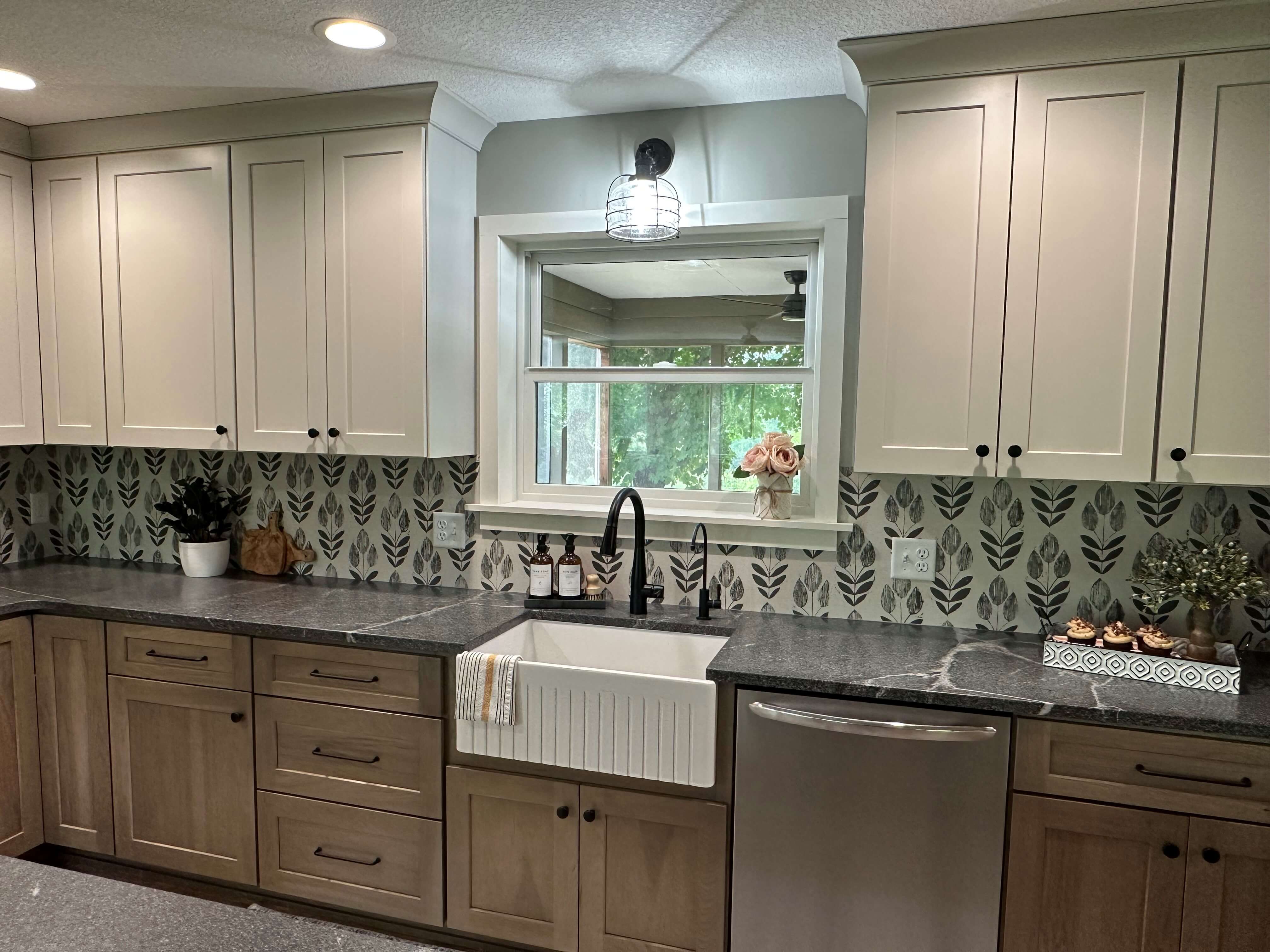 A kitchen with base cabinets in a stained wood finish and wall cabinets in a light painted finish.