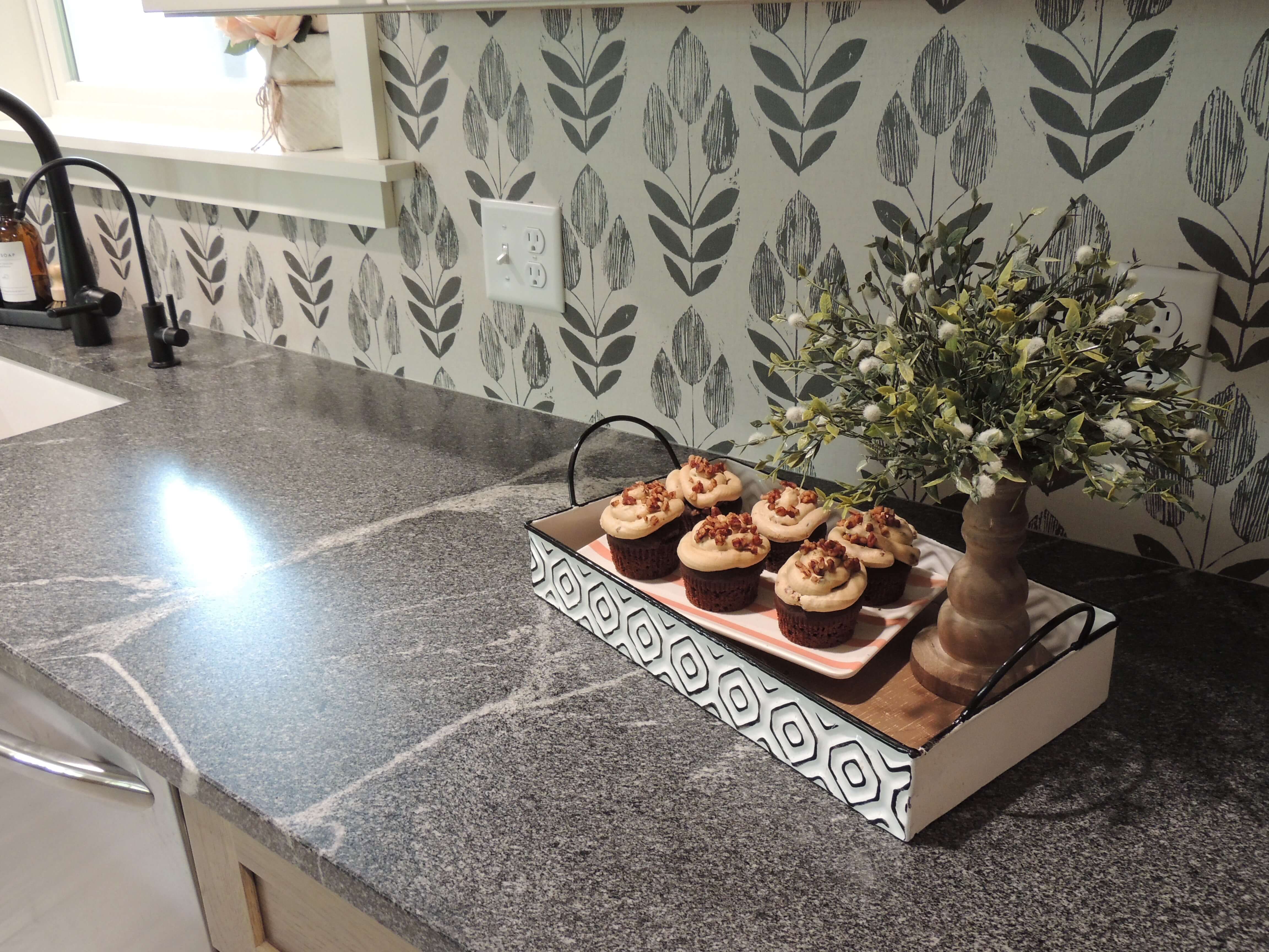 A close up of the honed granite countertop and leaf patterned backsplash in the newly remodeled kitchen.