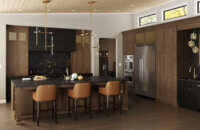 A modern kitchen with traditionally framed cabinets in a mix of brown stained wood and black stained wood.