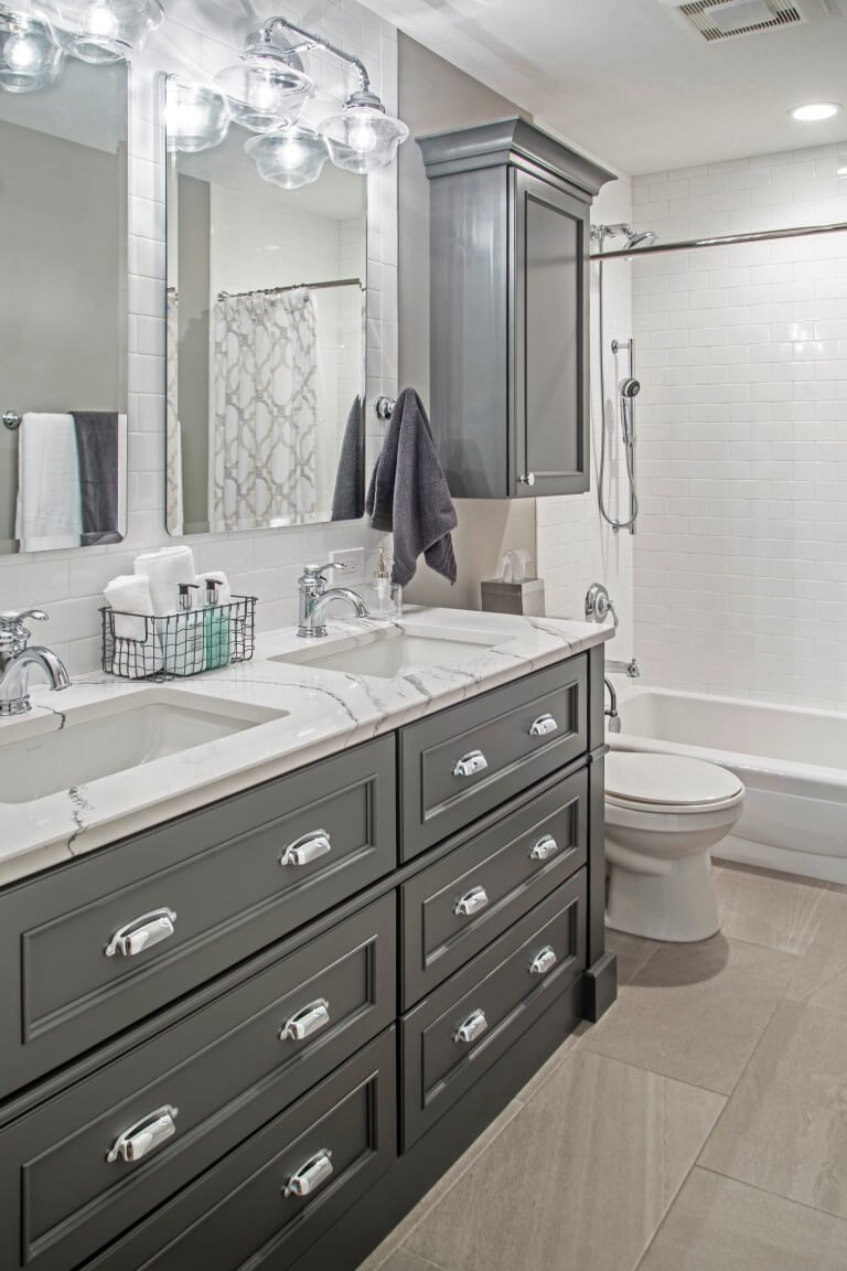 A dark gray painted furniture vanity with double sinks.