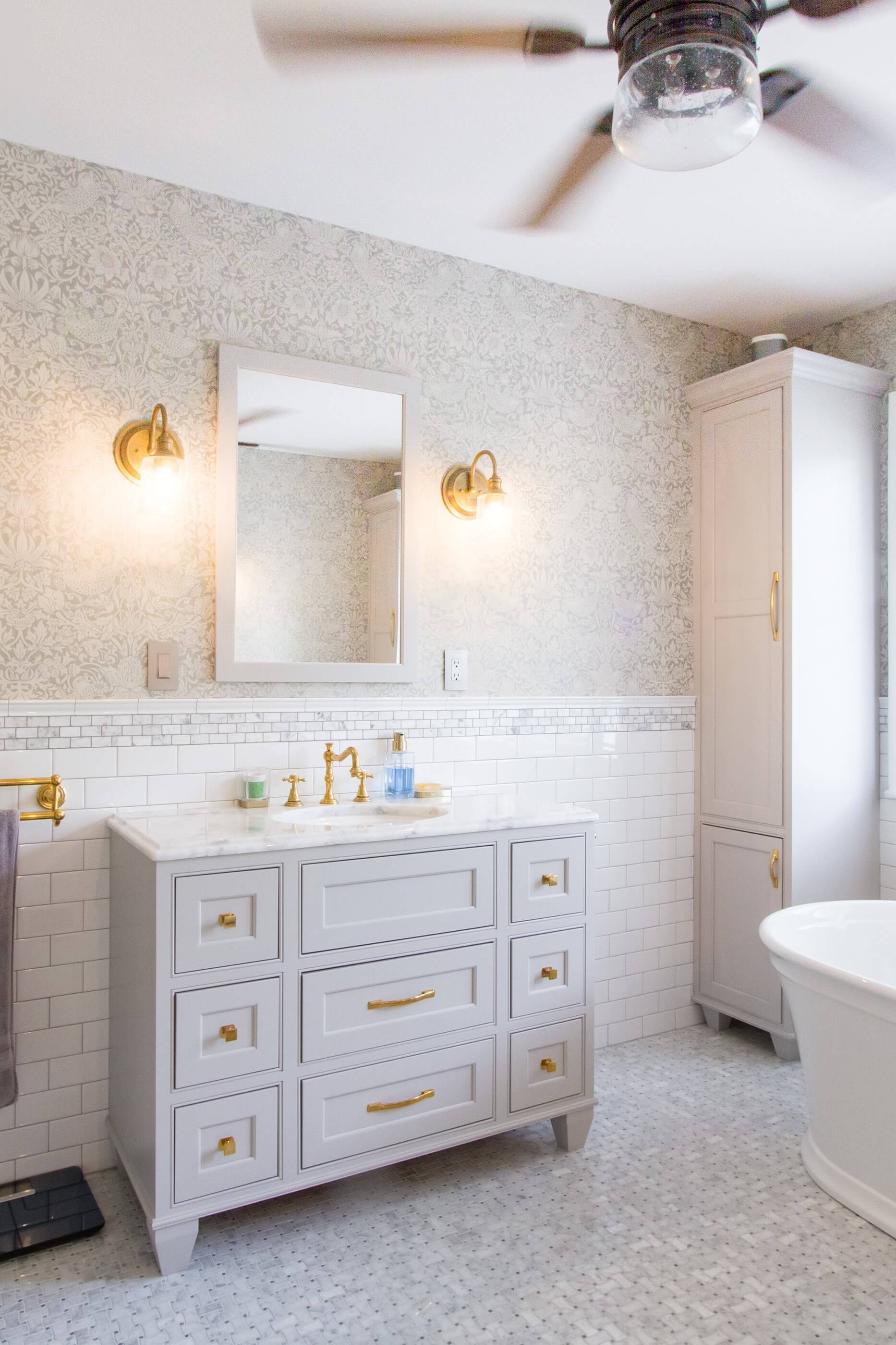 A light gray and transitional styled bath vanity with vanity legs featuring modern bun feet that elevate the cabinets from the floor.