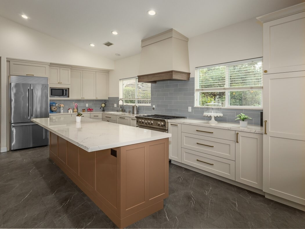 A white kitchen with a light wood kitchen island and white countertops featuring a subtle, off-white paint color for the cabinets.